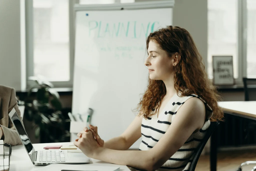 Emprendedora frente a su laptop en una oficina luminosa, planificando la estrategia de su negocio online