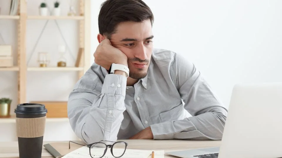 Emprendedor frustrado frente a su laptop sin recibir consultas de clientes